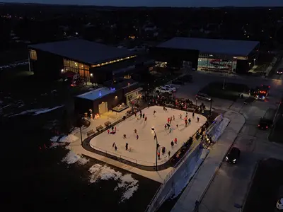 Aerial photo of the ice rink at night lit up with night time skaters enjoying the new rink.
