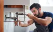 A plumber working on the pipes under a bathroom sink.