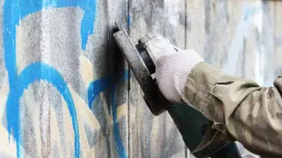 Removal of graffiti on a concrete wall with the help of a angle grinder.