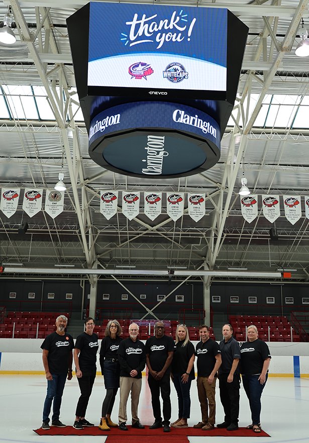 Regional Councillor Willie Woo; Julie Mitchell, Director of Community Services; Councillor Margaret Zwart; Mayor Adrian Foster; Regional Councillor Granville Anderson; Cheryl Littlejohn, North Shore Whitecaps President; Councillor Sami Elhajjeh; Phil Aitken, former Clarington Zone Vice President; and Jennifer Stycuk, Manager of Facilities, gather at Garnet B. Rickard Recreation Complex to celebrate the new scoreboard—an exciting boost for Clarington’s sports community.
