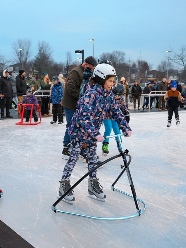 A young child uses a skate aid on the new ice rink.
