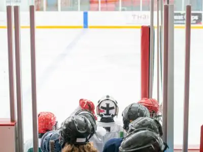 Group of youth dressed in hockey gear getting on the ice.