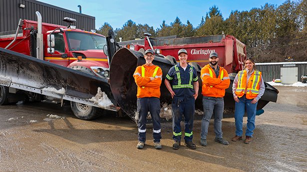 Clarington staff posing in front of a snowplow at the Hampton Works Depot