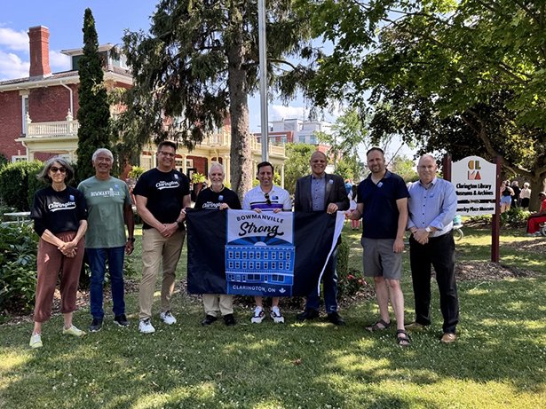 Local Councillor Ward 4 Margaret Zwart, Regional Councillor Ward 3 and 4 Willie Woo, Local Councillor Ward 2 Lloyd Rang, Mayor Adrian Foster, Local Councillor Ward 1 Sami Elhajjeh, MP Bowmanville-Oshawa, North Jamil Jivani, MP Northumberland-Clarke Philip Lawrence and representing the office of Todd McCarthy MPP for Durham, Douglas Ellis raise the Bowmanville Strong flag in a powerful symbol of unity and resilience.