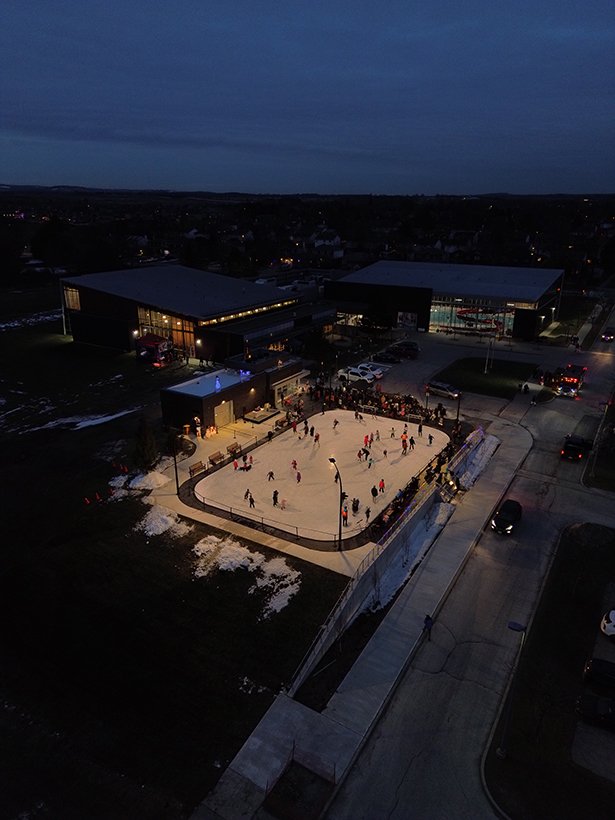 Aerial photo of the ice rink at night lit up with night time skaters enjoying the new rink.