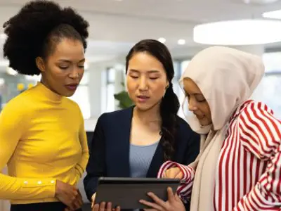 Diverse businesswomen with tablet working and talking in office.