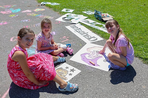 Children play with stencils and sidewalk chalk.