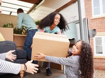Family unloading furniture from moving van into new home.