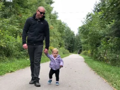 Father and toddler daughter walking