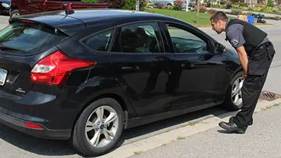 A by-law officer educating a driver at the passenger side window.