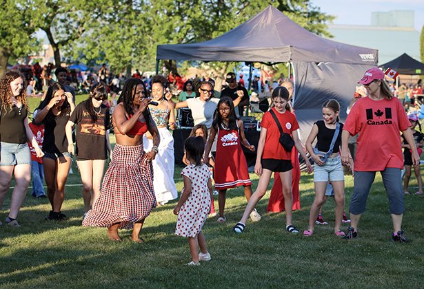 Singer from City Soul singing and teaching a dance to party goers on the park lawn