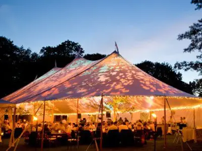 Special event tent lit up from the inside with dark blue night time sky and trees