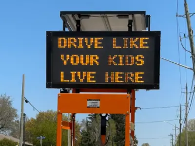 A digital sign with the message "Drive Like Your Kids Live Here."